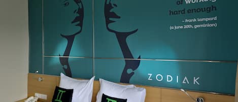 A hotel room with a large wall mural featuring a quote and zodiac signs.