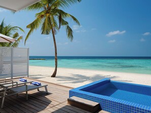 A wooden deck with lounge chairs and a small pool with blue tiles.