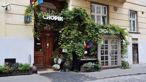 Kauppa nimeltä »Chopin», jonka julkisivu on tehty puusta, ja jonka edessä on ruukuissa olevia kasveja sekä mukulakivikatu.