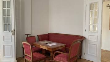A corner dining area with a wooden table and four red upholstered chairs.