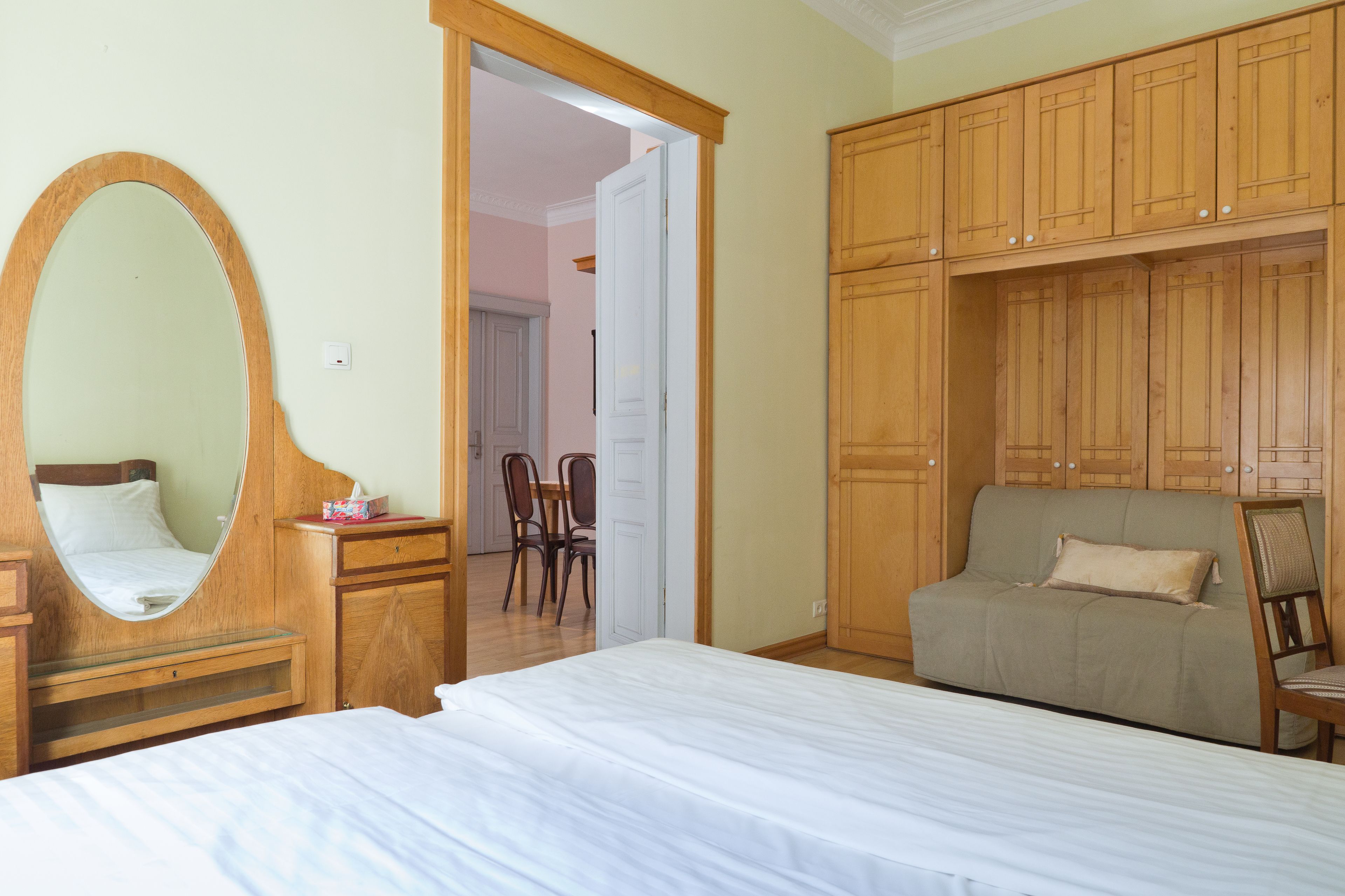 Un dormitorio con una cama grande, un armario de madera, un espejo y un sofá.