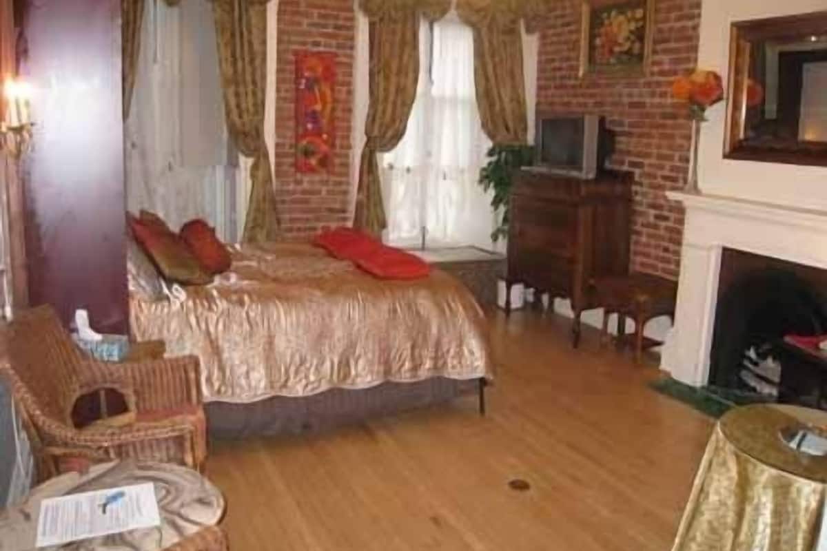 Una habitación con cama, televisión, chimenea y pared de ladrillo.