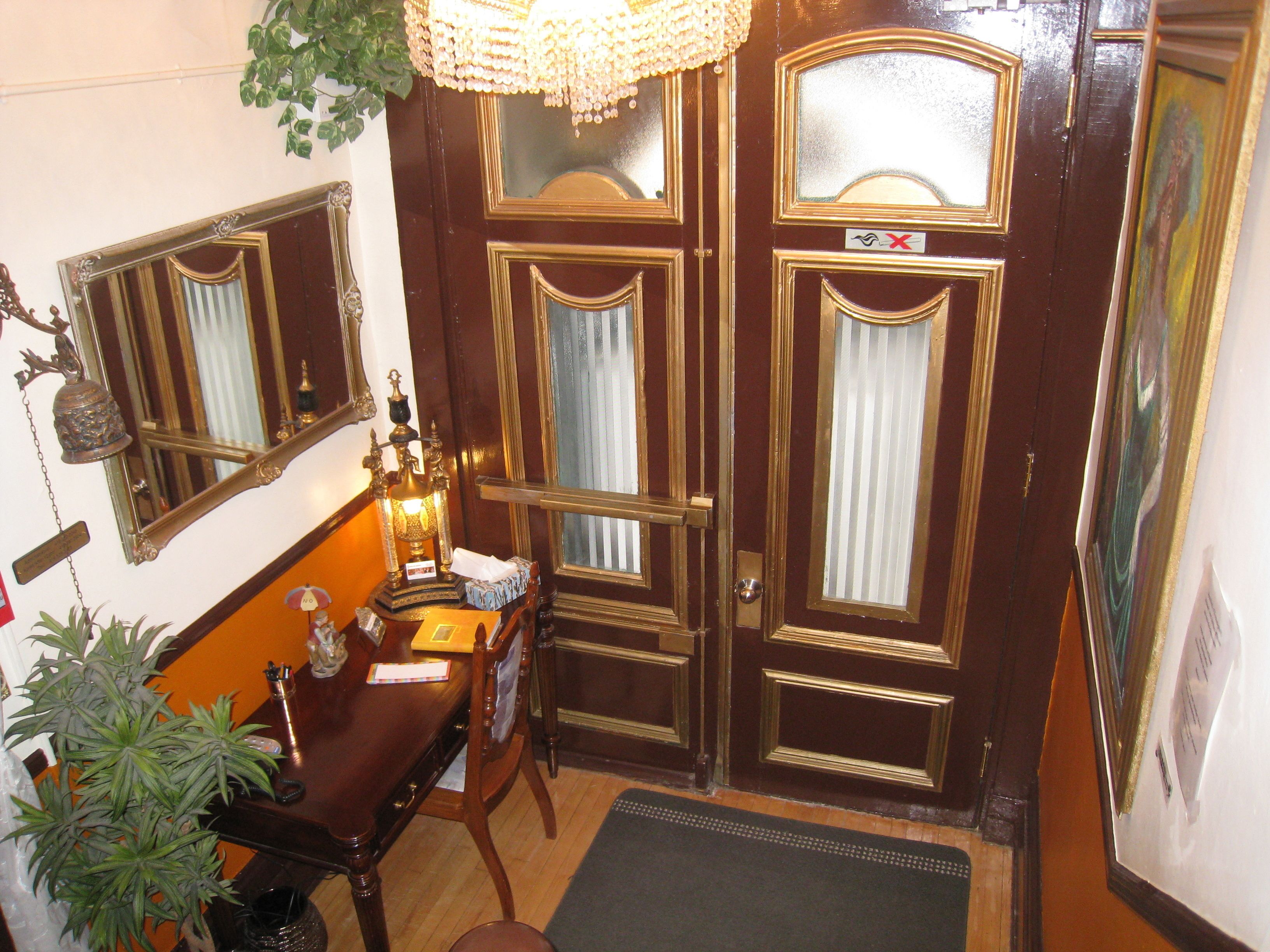 Una habitación con una puerta de madera, un escritorio con una lámpara y una planta en maceta.