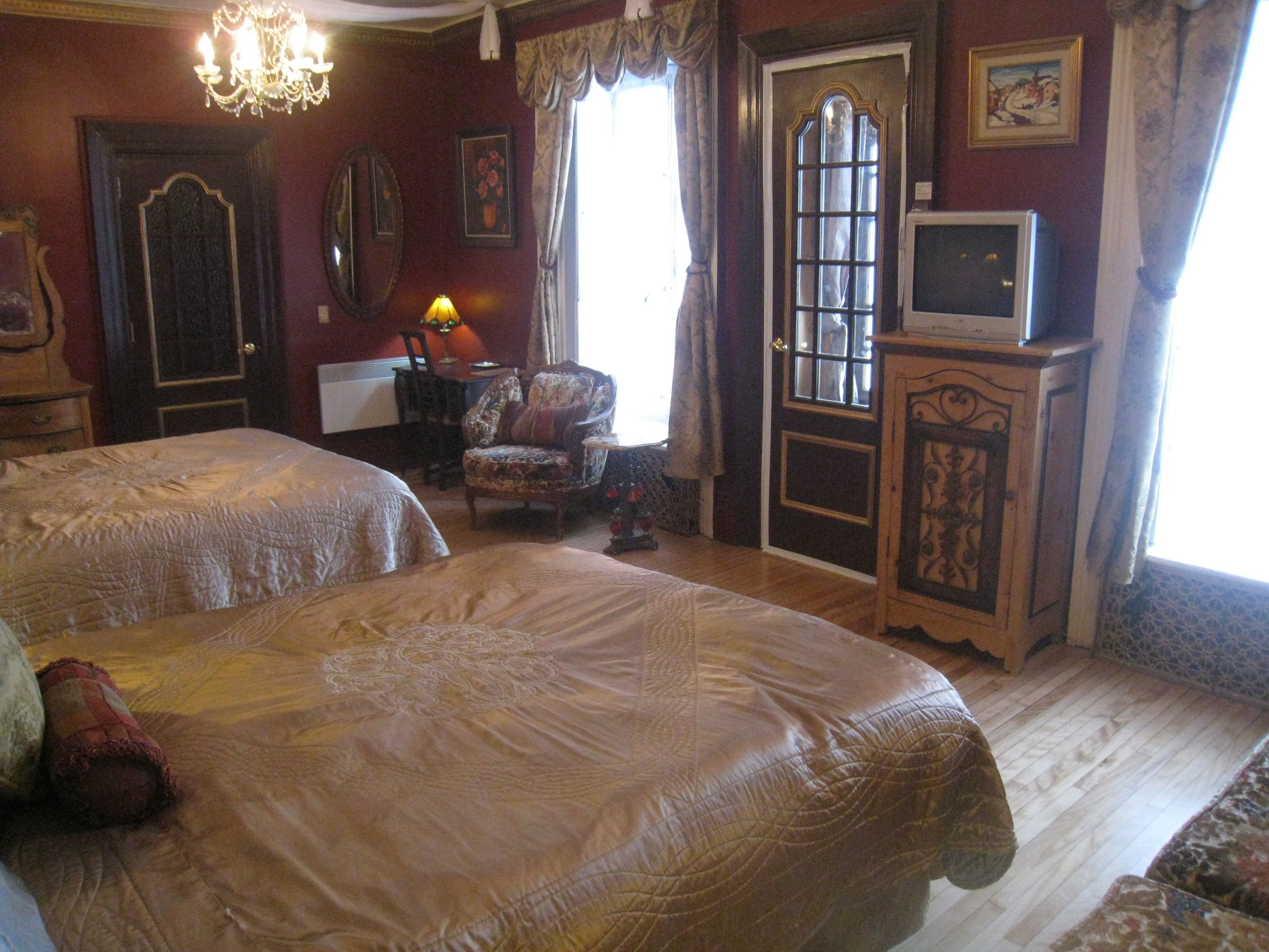 A room with two beds, a chair, a television, and a door with a window.