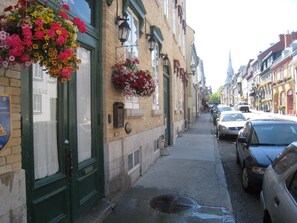 Eine enge Straße gesäumt von historischen Gebäuden, von denen einige Blumenkästen an den Fenstern tragen.