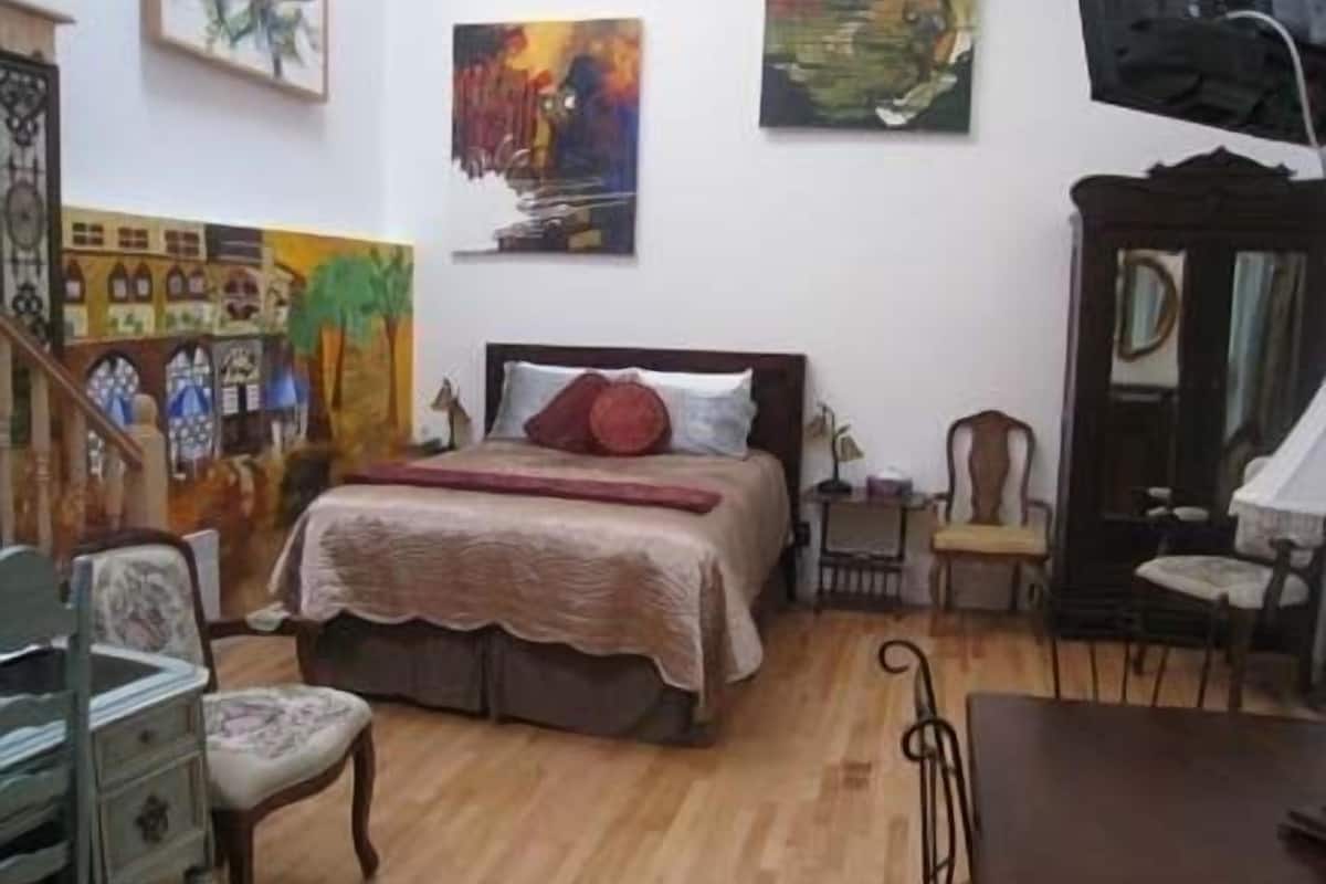 Un dormitorio con cama, una silla, un escritorio y un espejo.