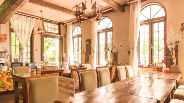 A restaurant with wooden tables and chairs, large windows, and hanging light fixtures. - Nikko Park Lodge Mountainside (Nikko)