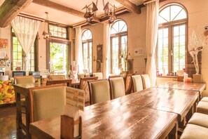 A restaurant with wooden tables and chairs, large windows, and hanging light fixtures. - Nikko Park Lodge Mountainside (Nikko)