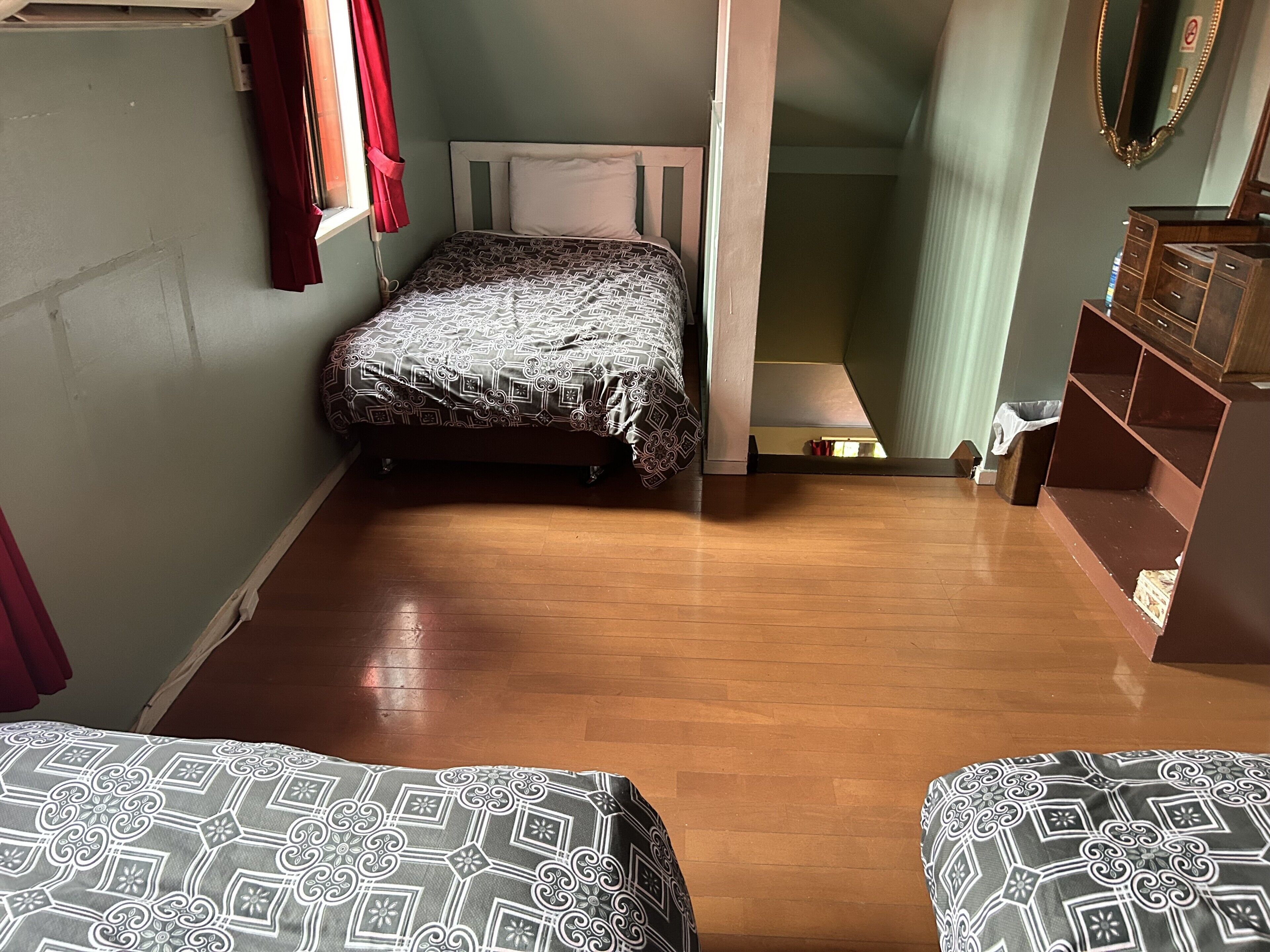 A room with a bed, a wooden dresser, and a small table.