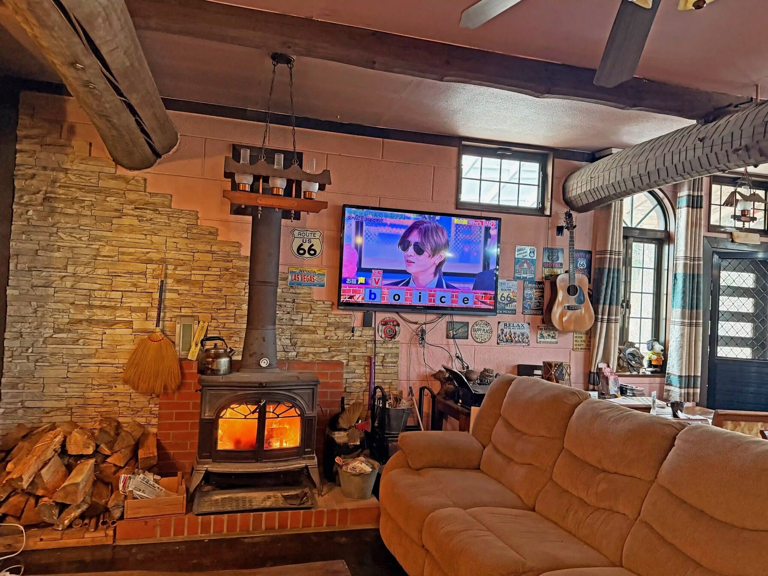 A cozy living room with a stone wall, a fireplace, a TV, and a couch.