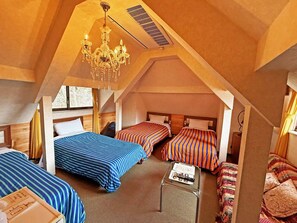 An attic room with three beds, a chandelier, and a small table with a remote control. - Nikko Park Lodge Mountainside (Nikko)