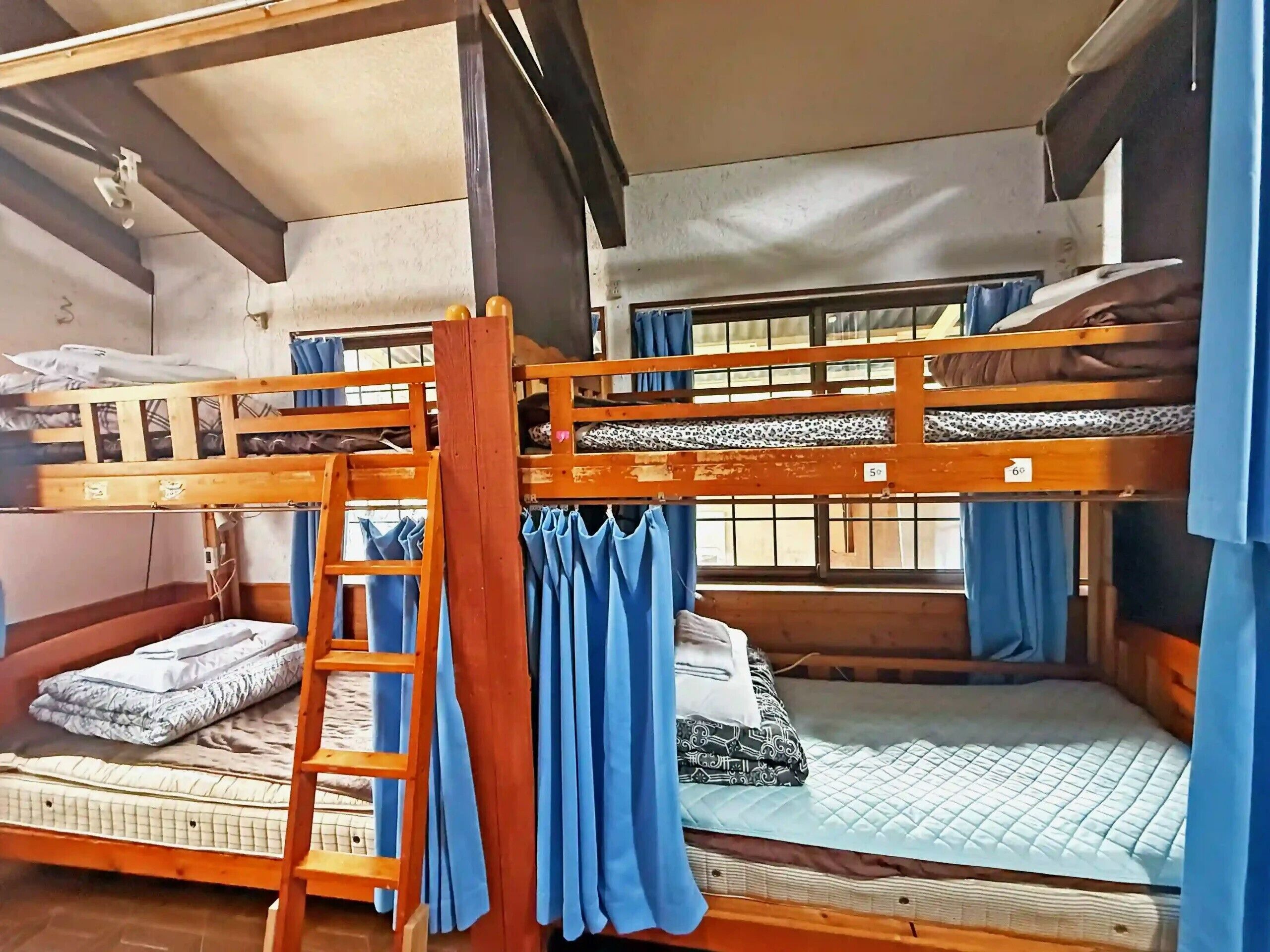 A bunk bed room with a ladder, curtains, and a window.