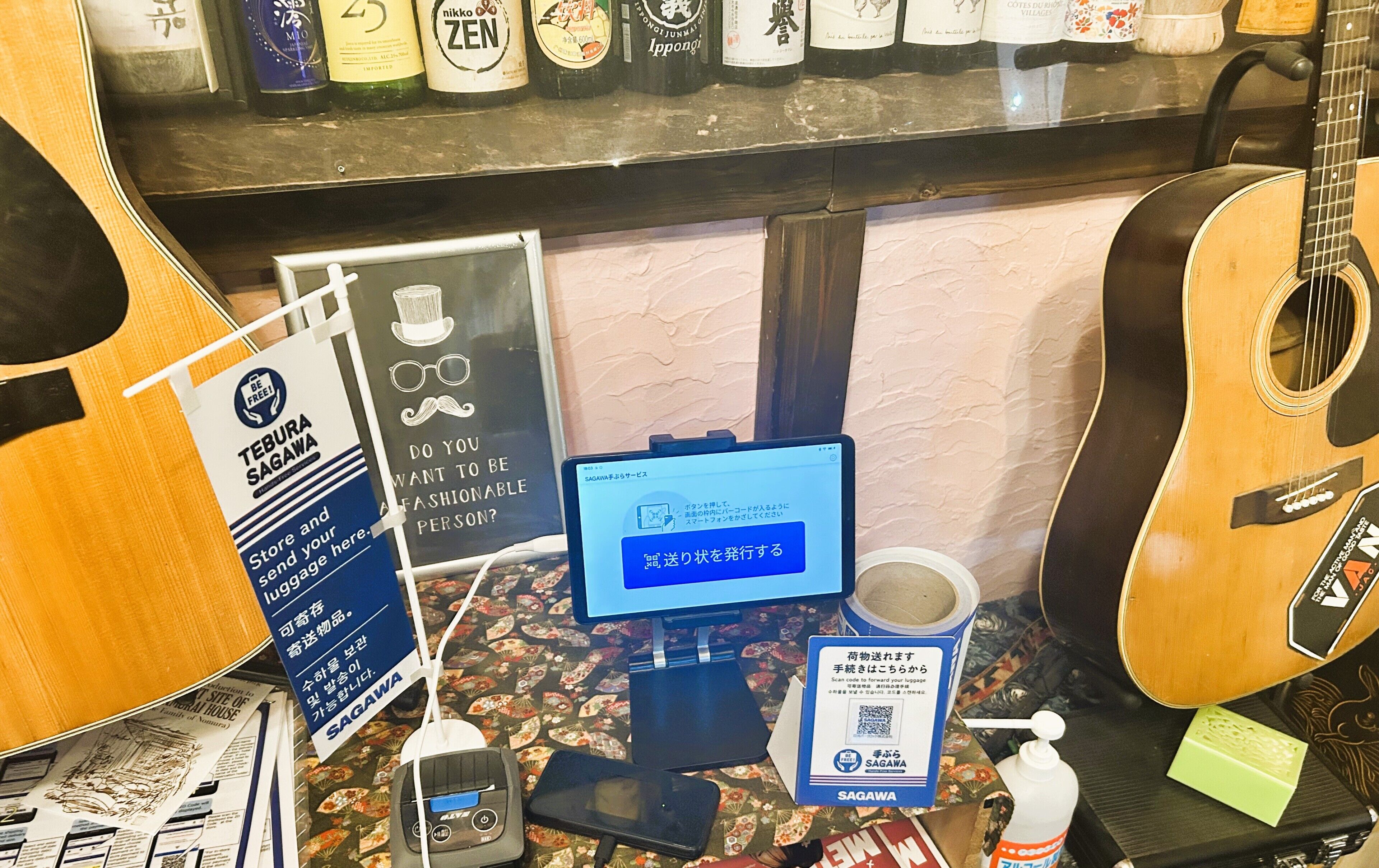 A room with a guitar, a computer, a sign, and a bottle.