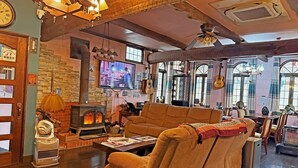 A cozy living room with a fireplace, comfortable seating, a television, and a rustic decor. - Nikko Park Lodge Mountainside (Nikko)