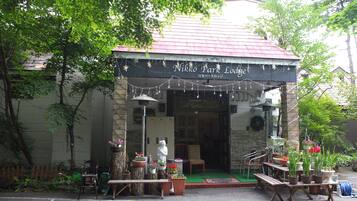 Experience the charm of Nikko Park Lodge, where lush greenery surrounds a rustic entrance and inviting seating areas.