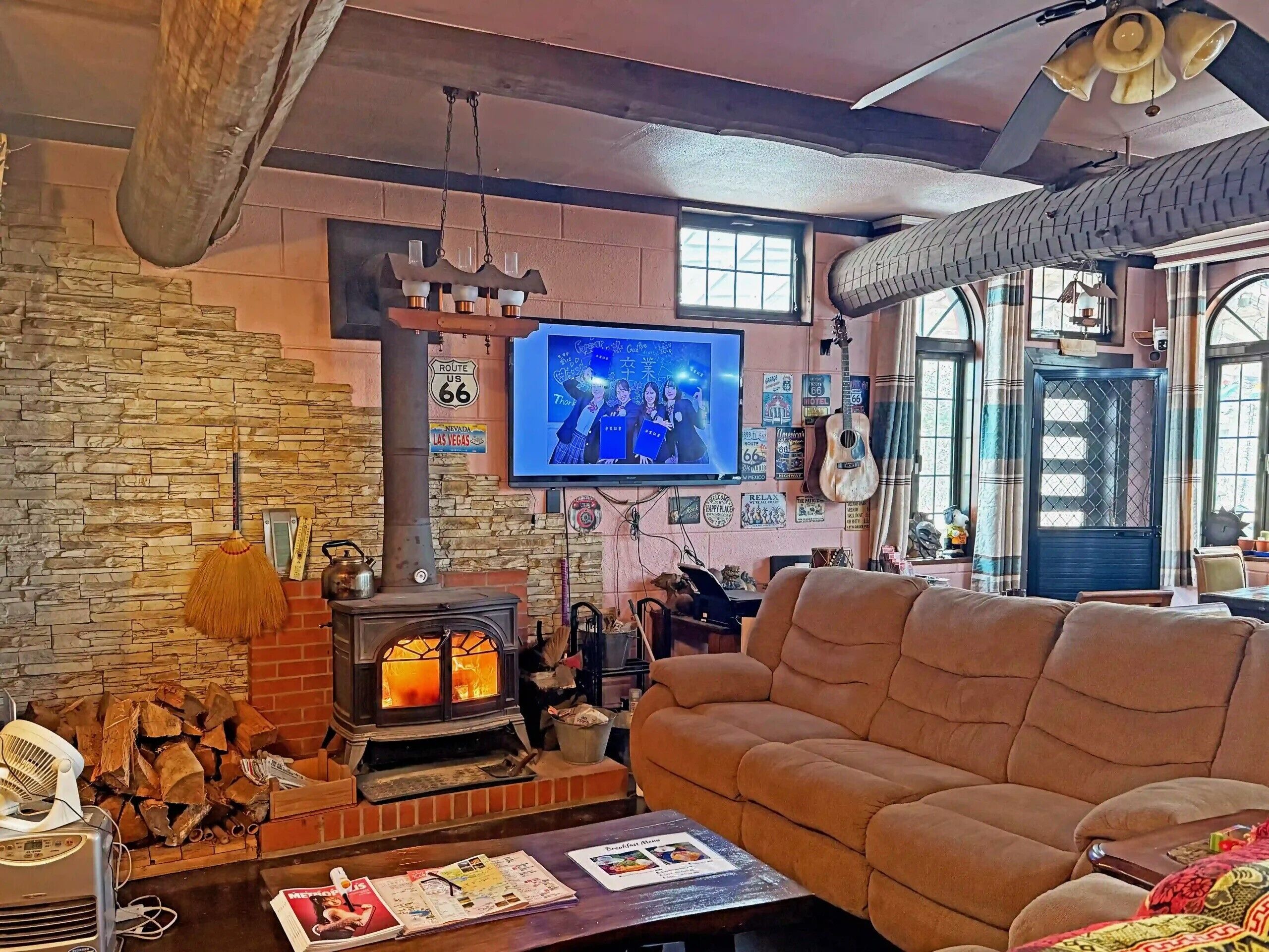 A cozy living room with a stone wall, a fireplace, a television, and a comfortable couch.