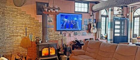 A cozy living room with a stone wall, a fireplace, a television, and a comfortable couch.