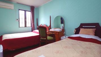 A hotel room with two beds, a desk, a chair, a mirror, and a window.