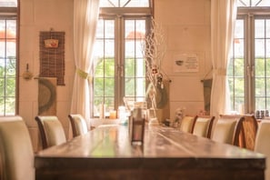 Un espace repas avec une longue table, des chaises et un vase décoré de branches.