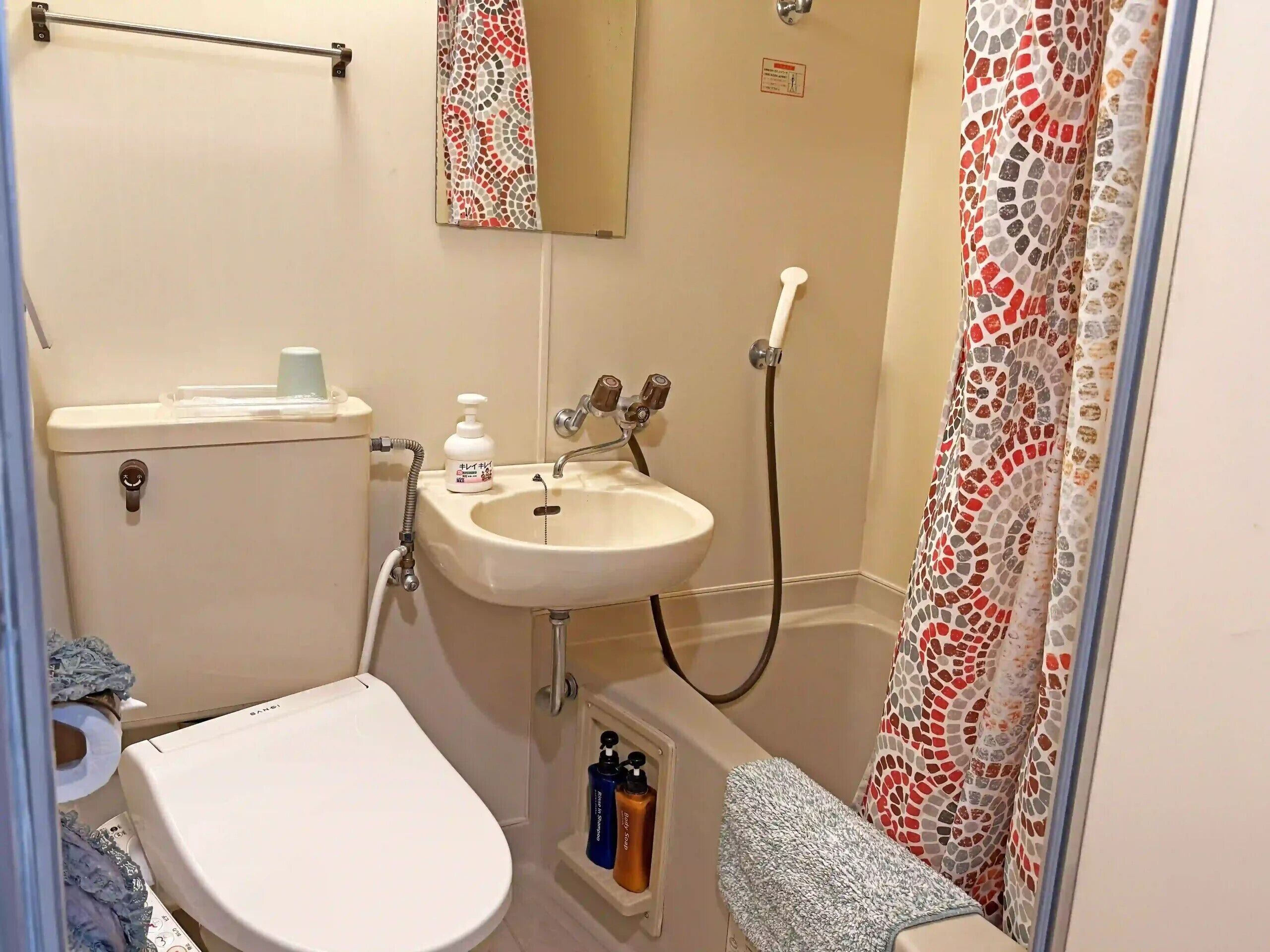 Un baño con inodoro, lavabo, ducha y un perchero para toallas.