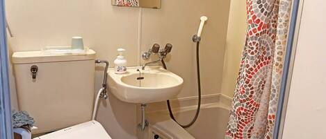 Un baño con inodoro, lavabo, ducha y un perchero para toallas.
