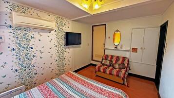 A room with a bed, a TV, a mirror, and a wardrobe.