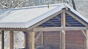 A covered outdoor barbecue area with a grill, chairs, and a table. - Nikko Park Lodge Mountainside (Nikko)