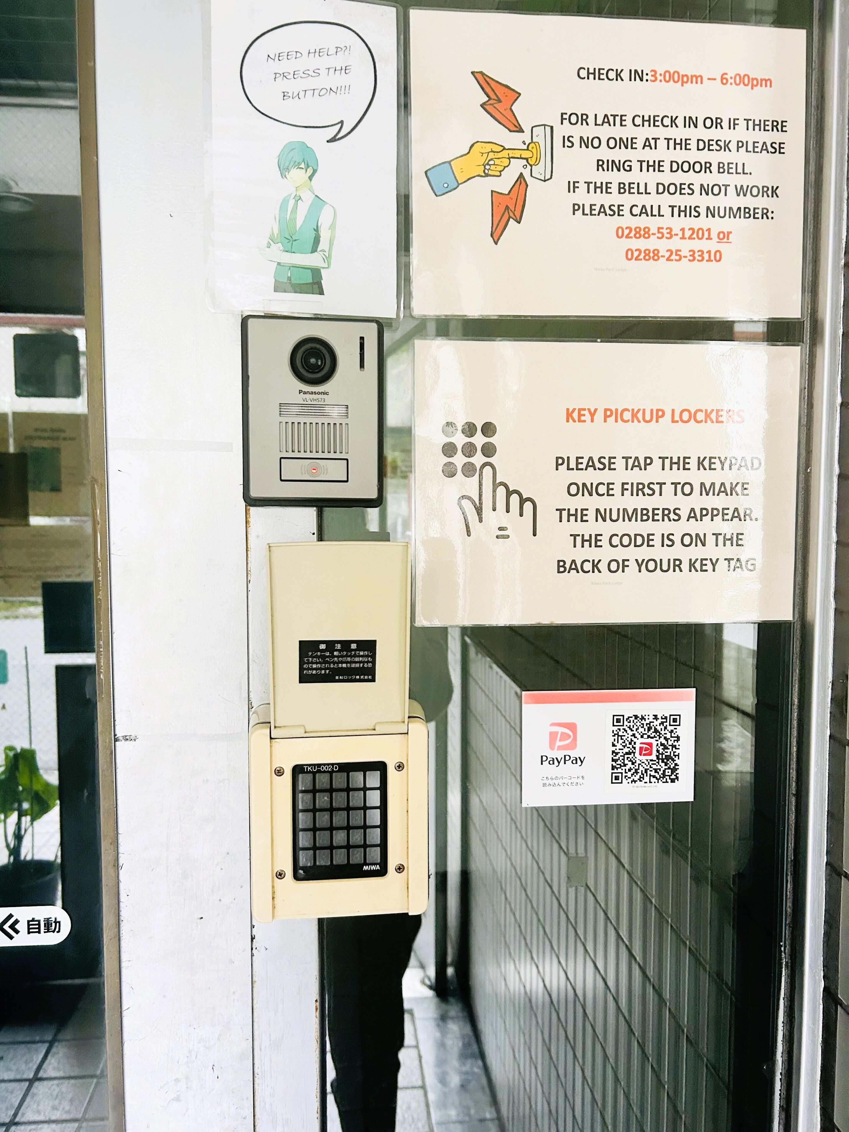 A security keypad, a surveillance camera, and multiple signs with instructions and contact numbers.