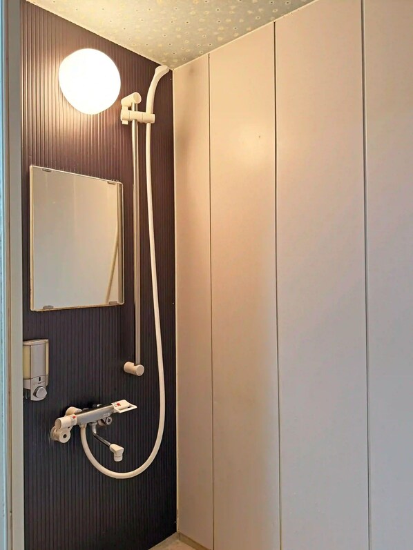 A bathroom with a shower, a mirror, and a soap dispenser. - Nikko Park Lodge Tobu Station (Nikko)