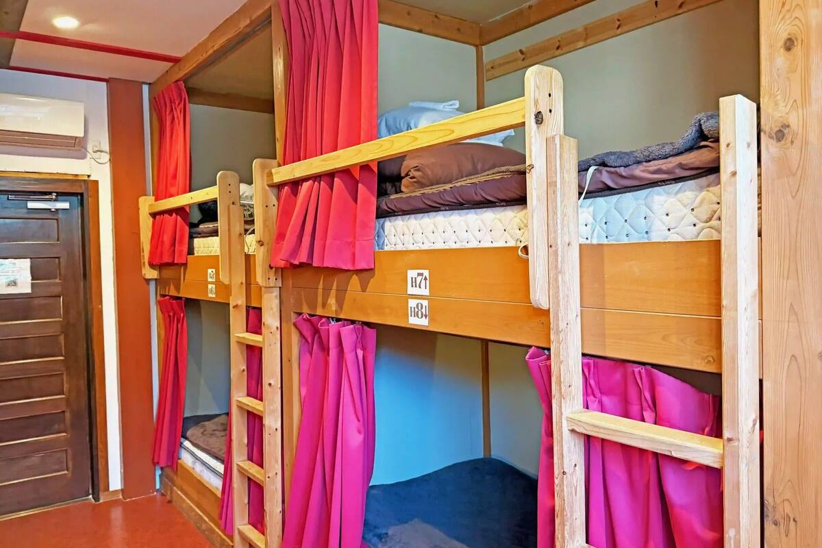 Bunk beds with curtains, a wooden door, and a wall-mounted air conditioner.