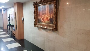 Un corridoio con pavimento in marmo, un quadro incorniciato al muro e una statua su un piedistallo.