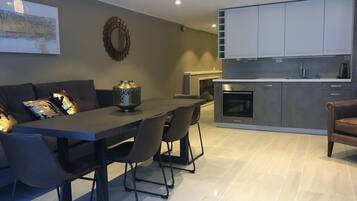 Una cocina moderna con gabinetes grises, horno empotrado y una zona de comedor con mesa y sillas grises.