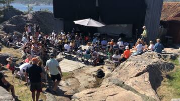 An outdoor amphitheater with a stage and audience seating on rocky terrain.