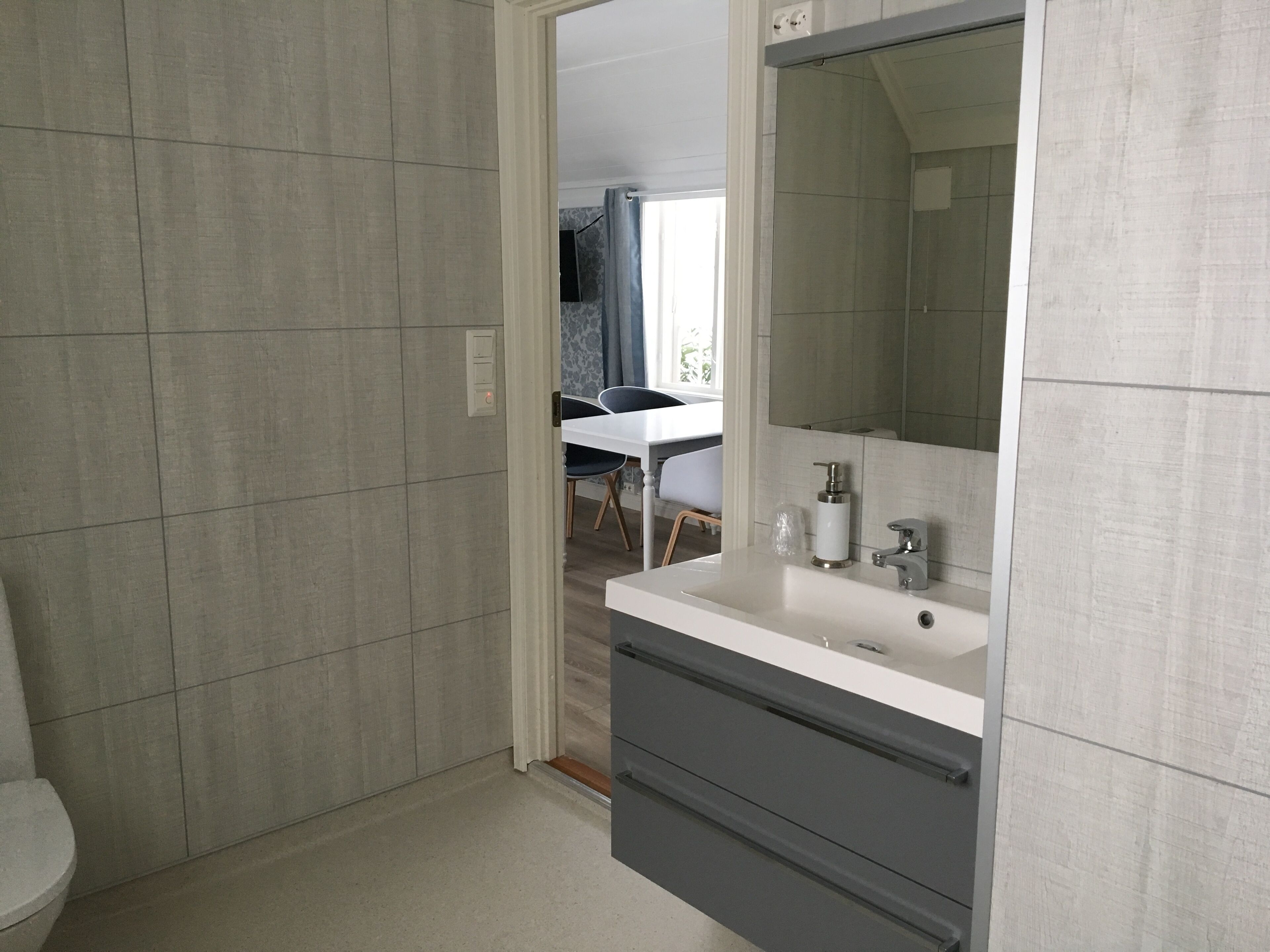 Une salle de bain moderne avec un lavabo blanc, un grand miroir et des meubles de couleur grise.