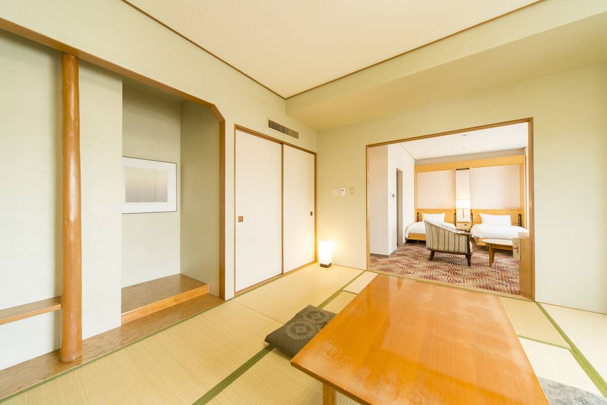 Une pièce de style japonais traditionnel, avec un sol recouvert de tatamis, une table en bois et un lit doté d’un oreiller et d’une petite table de chevet.