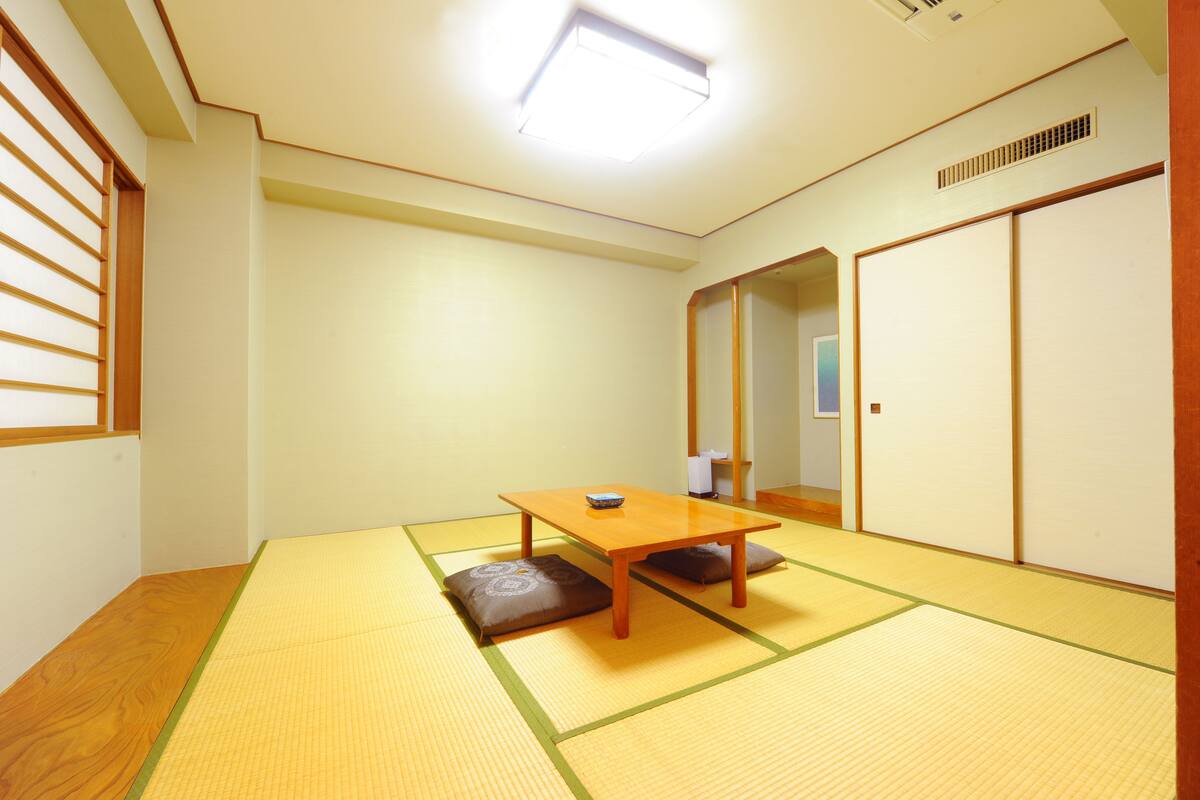 Une pièce de style japonais traditionnel, avec un sol recouvert de tatamis, une petite table en bois et des portes coulissantes en papier de riz (shoji).