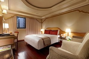 Una habitación de hotel con una cama grande, una silla, un escritorio y una ventana con cortinas.