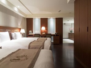 Une chambre d’hôtel avec deux lits, un bureau, une chaise, une table de chevet et une armoire.