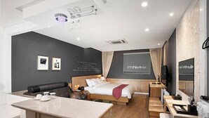 Una habitación de hotel moderna con cama, escritorio, sofá y una pequeña kitchenette.