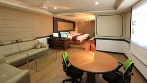 Una habitación de hotel con cama, escritorio con computadora, sofá y mesa de comedor con sillas.