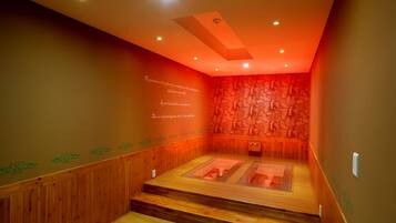 A sauna room with wooden benches and a stone wall.