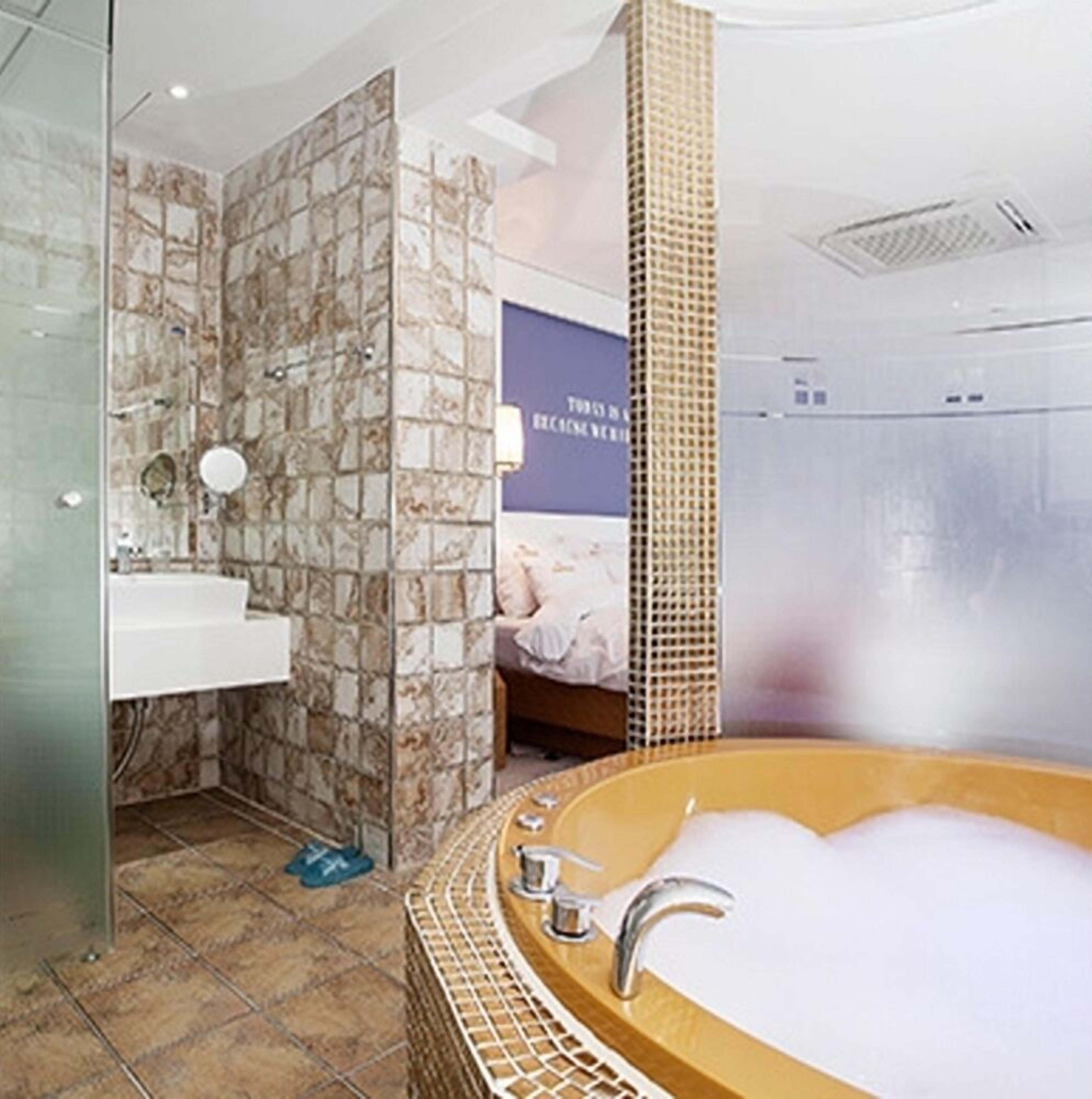 A bathroom with a stone wall, a sink, a bathtub, and a shower area.