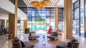 Um hall amplo com móveis modernos, janelas grandes e um lustre único.