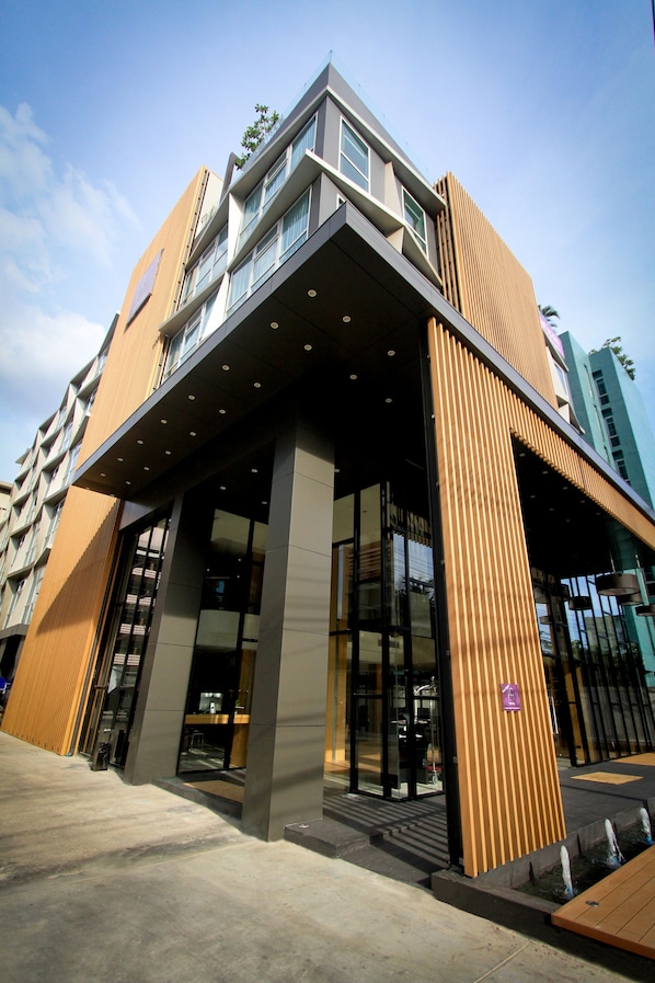 Un edificio moderno con ingresso in vetro, facciata in legno e cielo sereno.