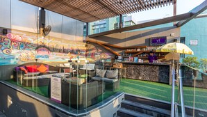 Uma área externa com mobiliário de vime e um bar.