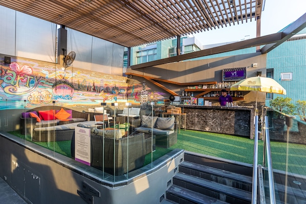 Een terras met rieten meubilair en een bar.