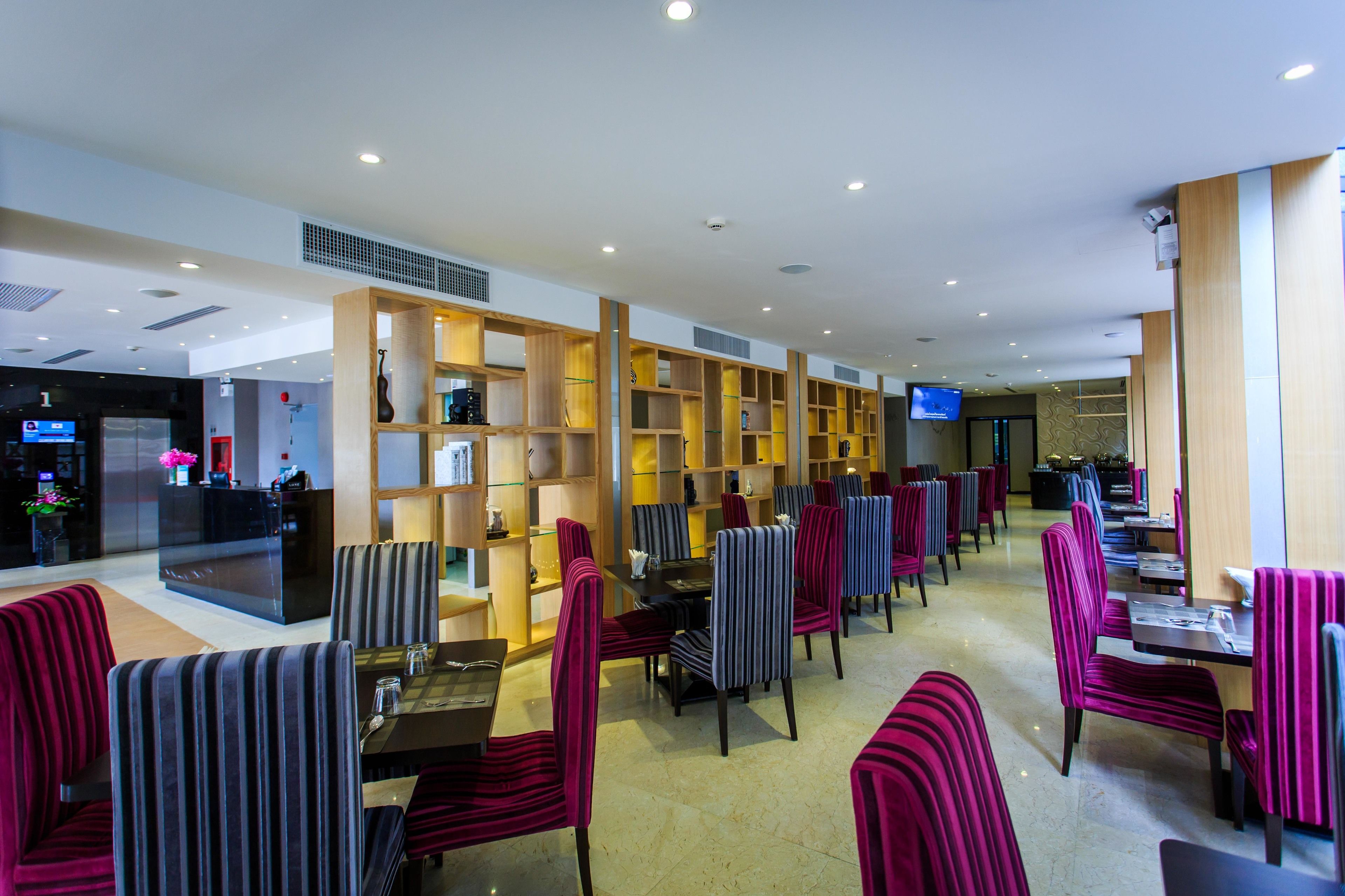 Un restaurant avec des chaises et des tables à rayures, un comptoir d’accueil et un écran de télévision.
