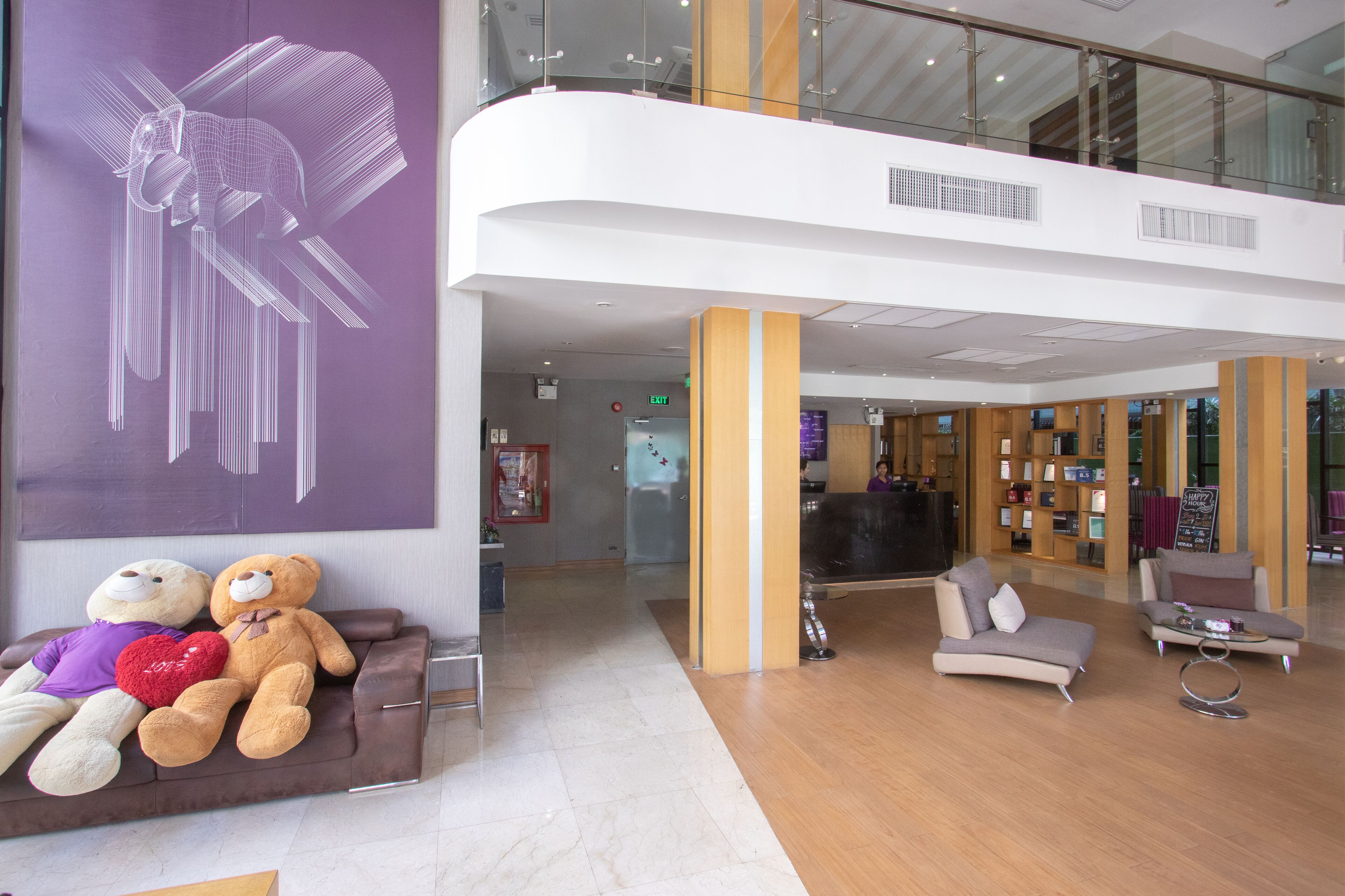 En lobby med receptionsdisk, siddeområde med sofaer og et stort kunstværk på væggen.