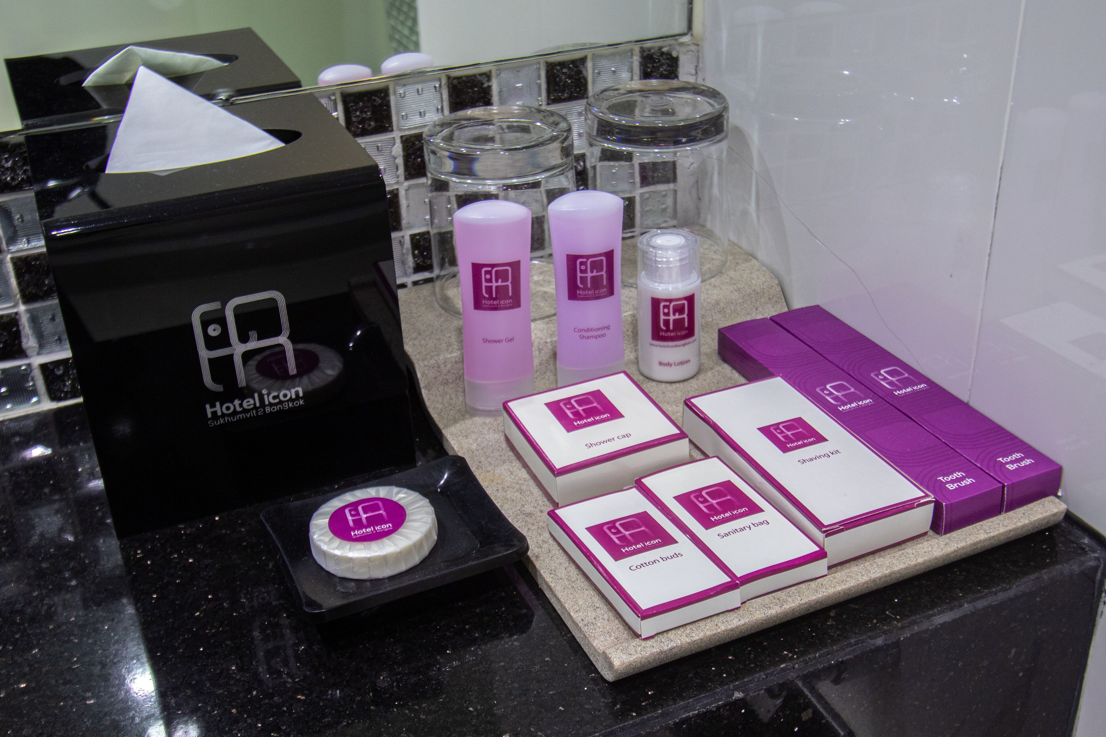 A hotel bathroom counter with various toiletries and a tissue box.