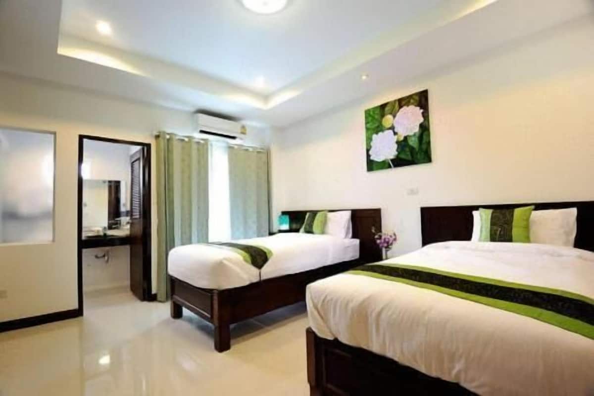 A hotel room with two beds, a bathroom, and a large window with curtains.